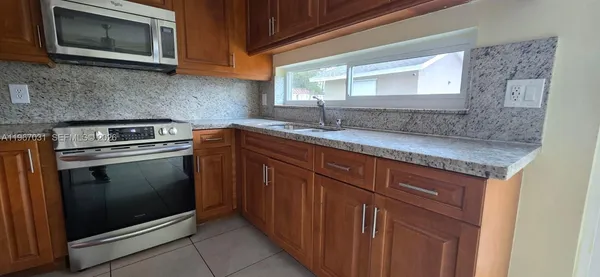 a kitchen with granite countertop a sink stove and microwave