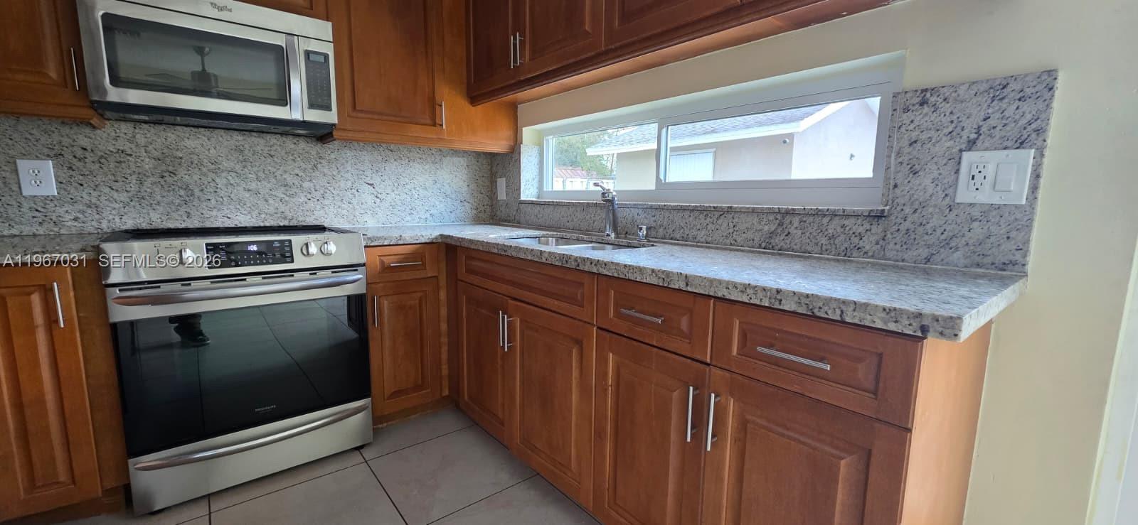 5900 Atlanta Street Hollywood, FL 33021 - Photo 4 of 21 a kitchen with granite countertop a sink stove and microwave