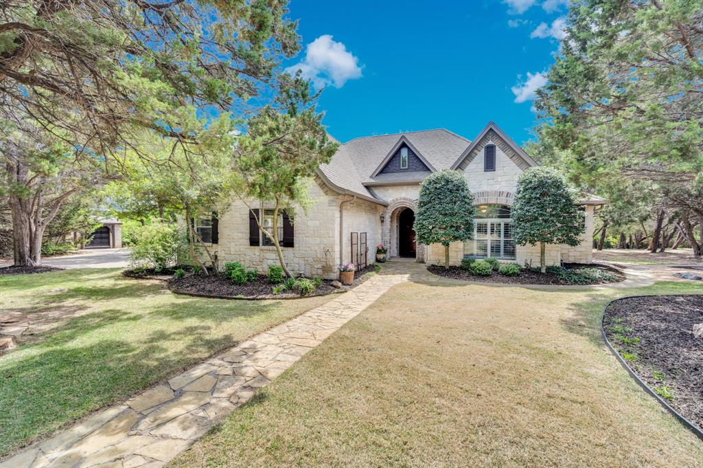 Beautiful stone exterior with mature trees and inviting front walkway.