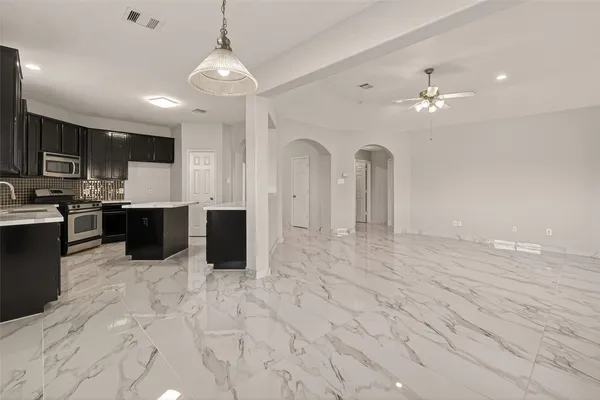 a view of a kitchen with kitchen island stainless steel appliances refrigerator cabinets and microwave