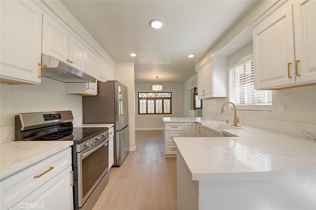9118 Maple Street Bellflower, CA 90706 - Photo 12 of 74 a kitchen with stainless steel appliances granite countertop a sink a stove and a refrigerator with wooden cabinets