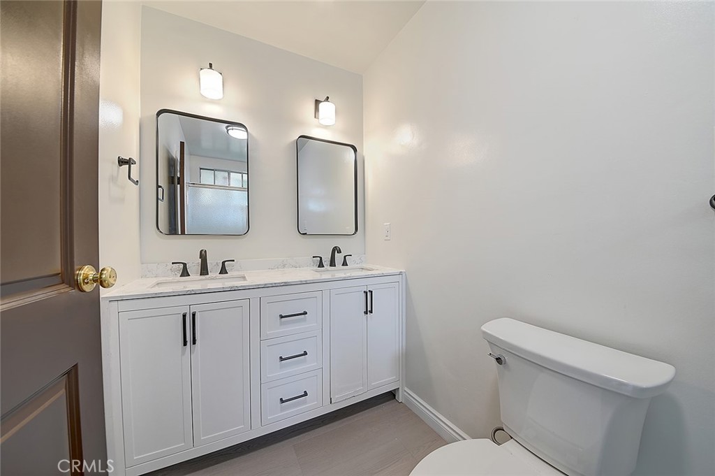 9118 Maple Street Bellflower, CA 90706 - Photo 49 of 74 a bathroom with double vanity sink a mirror and a toilet