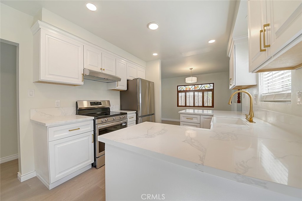 9118 Maple Street Bellflower, CA 90706 - Photo 10 of 74 a kitchen with stainless steel appliances kitchen island granite countertop a stove a sink a refrigerator and white cabinets with wooden floor