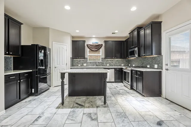 a kitchen with stainless steel appliances kitchen island granite countertop a refrigerator a stove and a sink
