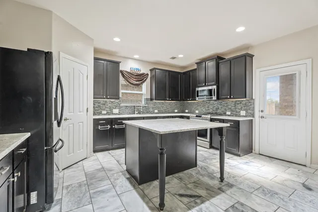 a kitchen with kitchen island granite countertop a sink stove and refrigerator