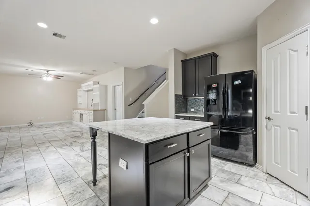 a kitchen that has a kitchen island wooden cabinets and stainless steel appliances