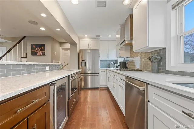 a kitchen with counter top space a sink wooden floor and stainless steel appliances