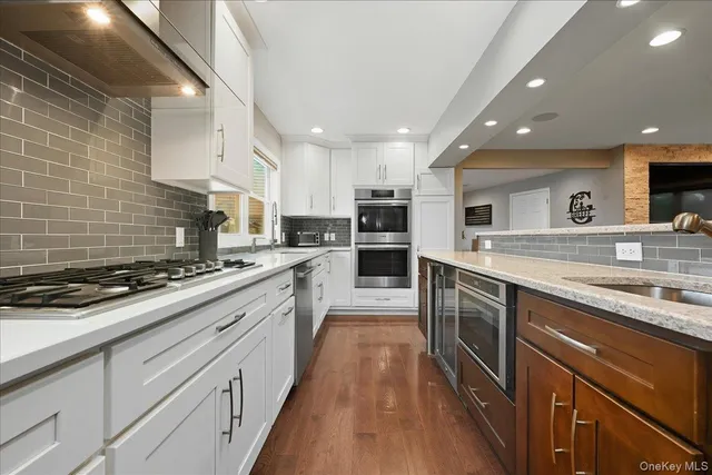 a large kitchen with stainless steel appliances granite countertop a lot of counter space and wooden floors