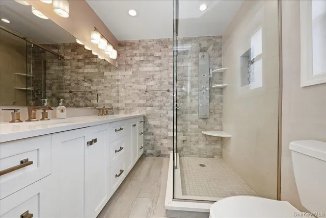 a bathroom with a double vanity sink toilet and shower
