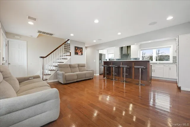 a living room with furniture a wooden floor and a kitchen