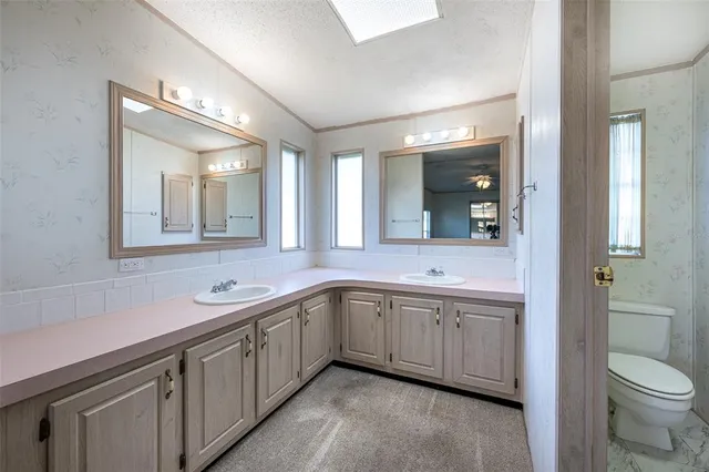 a spacious bathroom with a double vanity sink a toilet and a mirror