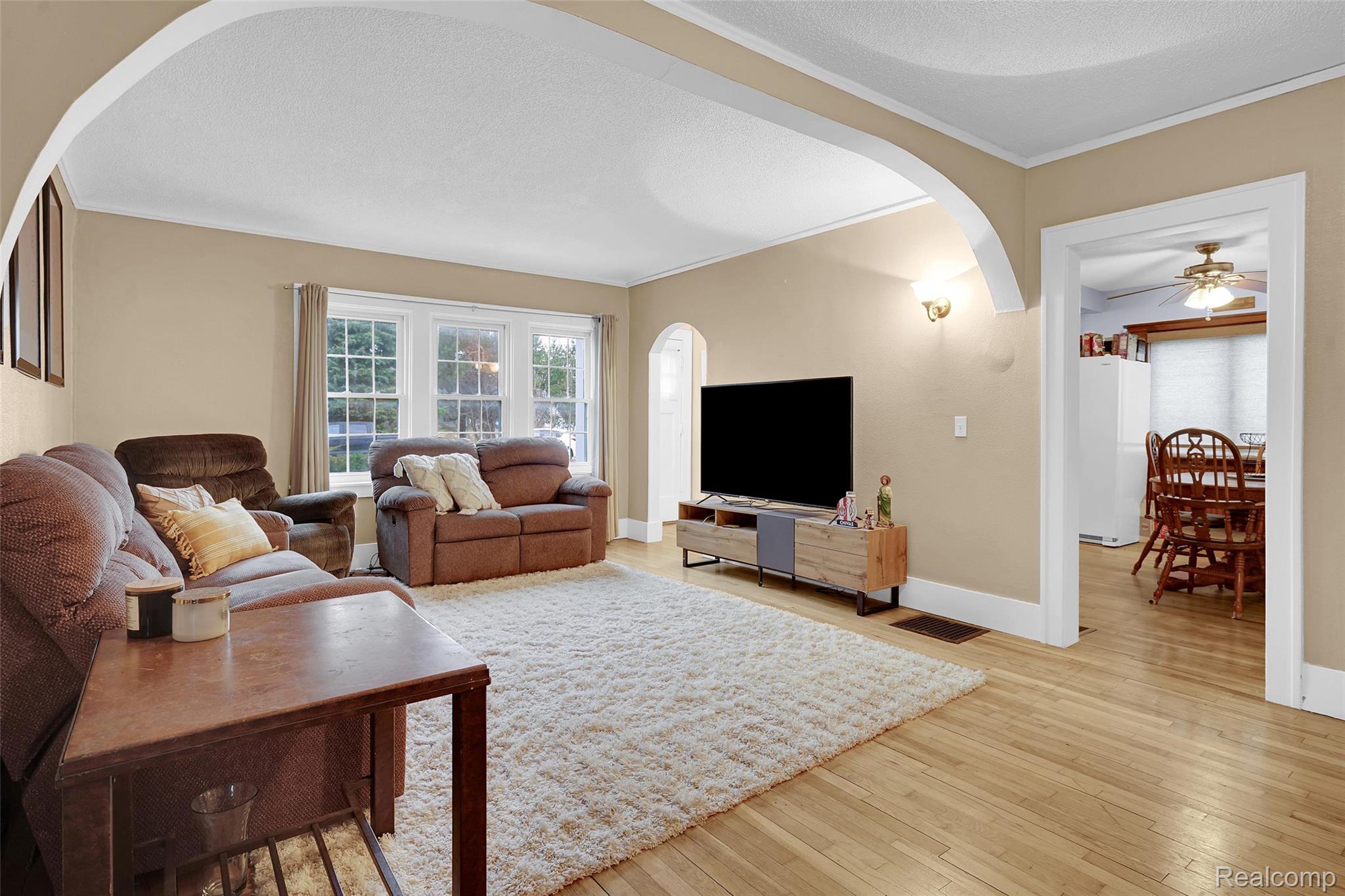 7972 3rd Street Forestville, MI 48434 - Photo 14 of 35 Living room with arched walkways, light wood-style flooring, ceiling fan, crown molding, and a textured ceiling