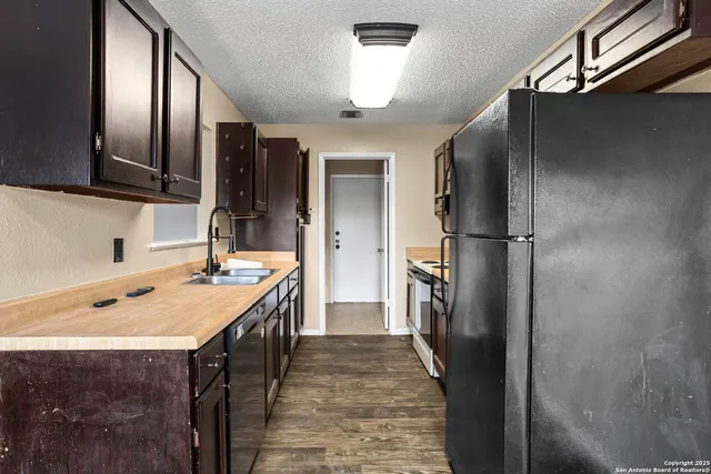a kitchen with a sink refrigerator and cabinets