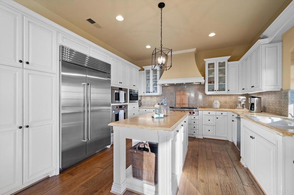7089 Heron Circle Carlsbad, CA 92011 - Photo 16 of 58 a kitchen with stainless steel appliances granite countertop a sink a stove a refrigerator and island with wooden floor