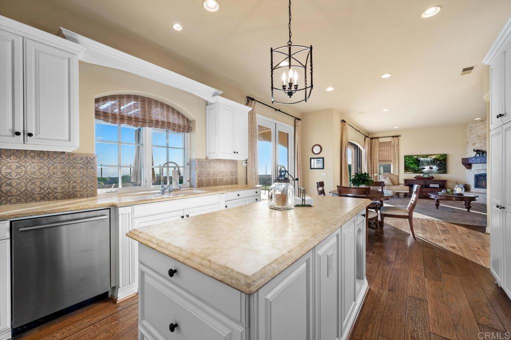 7089 Heron Circle Carlsbad, CA 92011 - Photo 19 of 58 a open kitchen with stainless steel appliances granite countertop a sink dishwasher a stove and a dining table with wooden floor