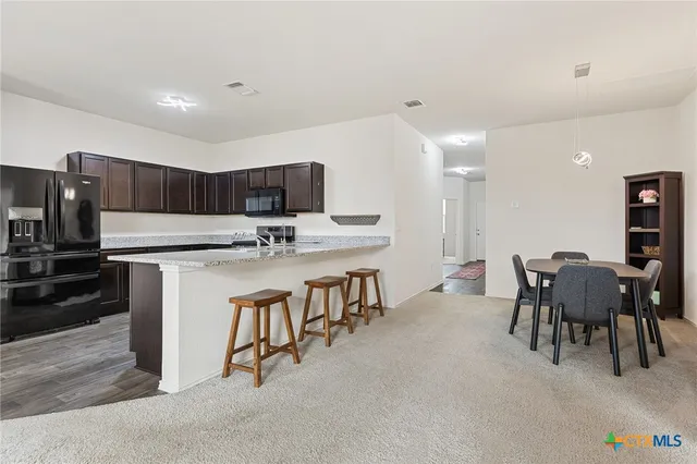 a kitchen with stainless steel appliances a table chairs and a refrigerator