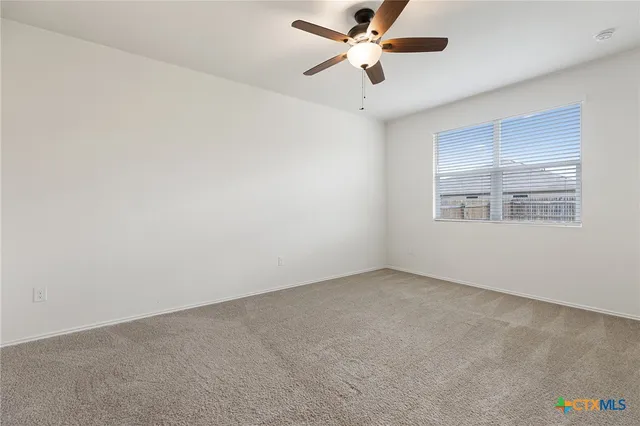 an empty room with windows and ceiling fan
