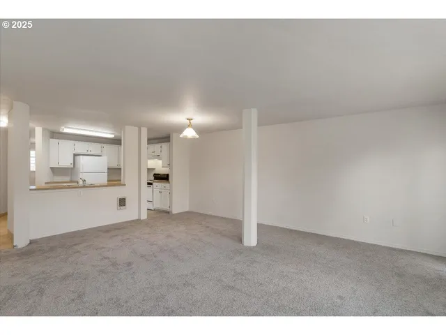 a view of an empty room and a kitchen