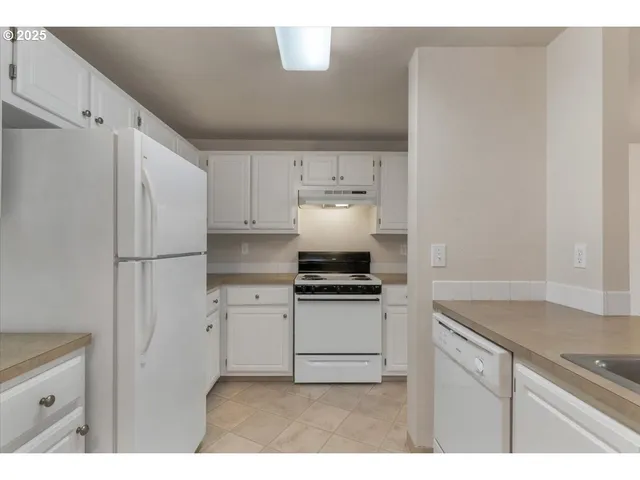 a kitchen with stainless steel appliances granite countertop a refrigerator a stove and white cabinets