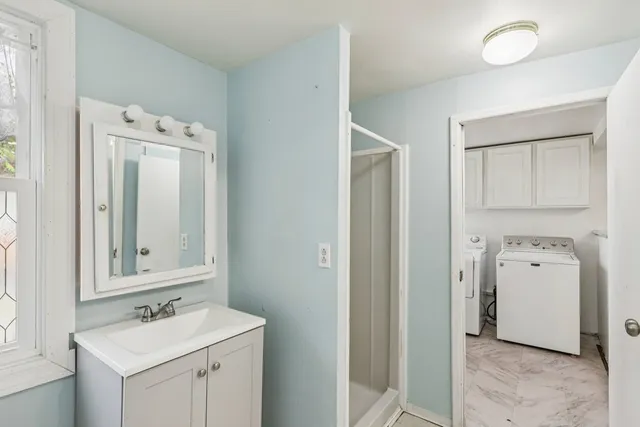 a view of bathroom with a sink mirror and window