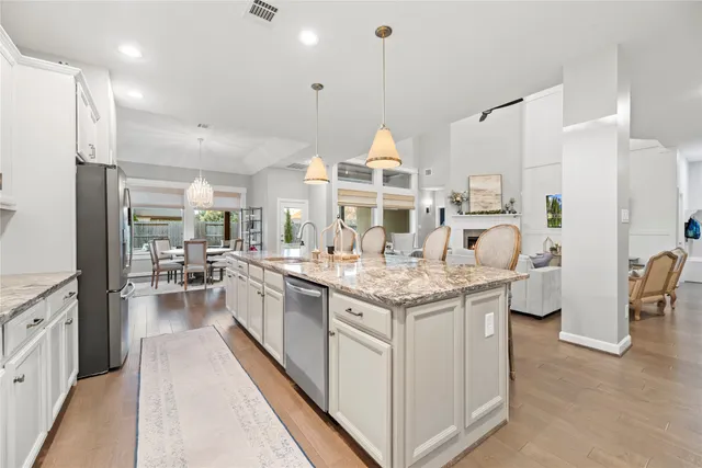 a kitchen with kitchen island granite countertop lots of white stainless steel appliances and white cabinets