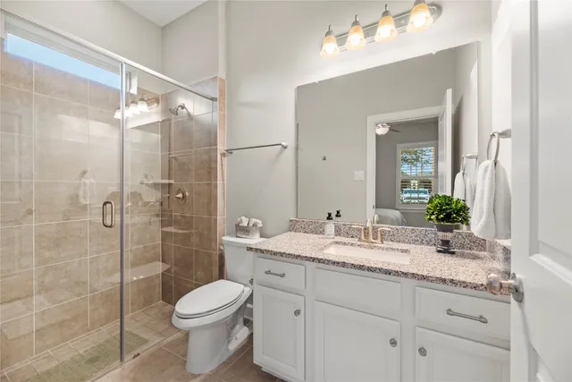 a bathroom with a granite countertop sink a toilet and shower