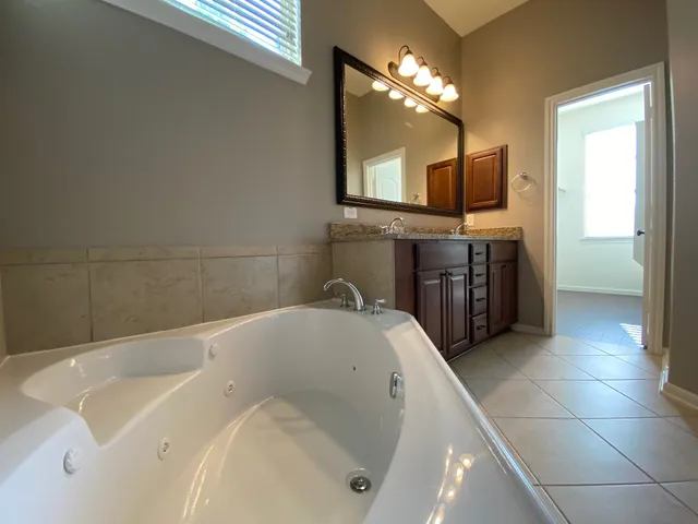 a bathroom with a tub sink and mirror