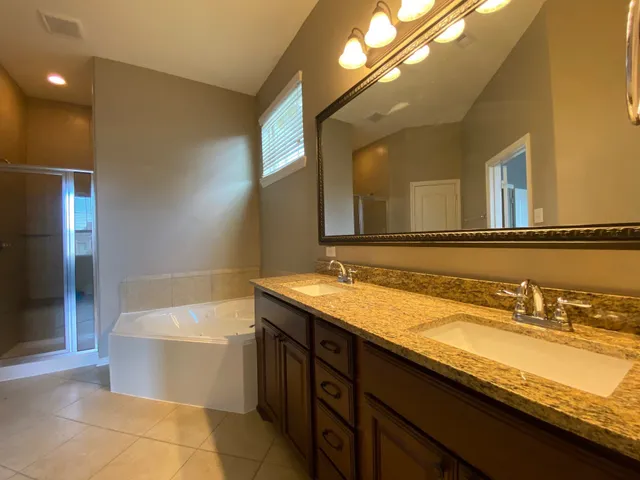 a bathroom with a granite countertop sink a toilet a mirror and bathtub