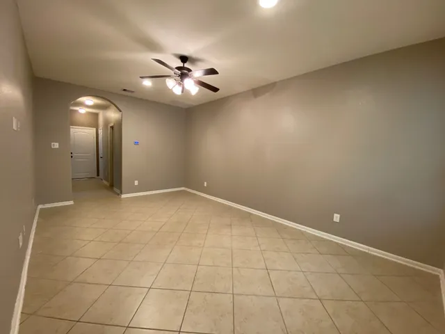 an empty room with a chandelier fan and windows