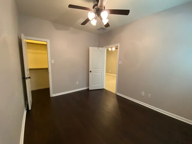 an empty room with wooden floor closet and windows