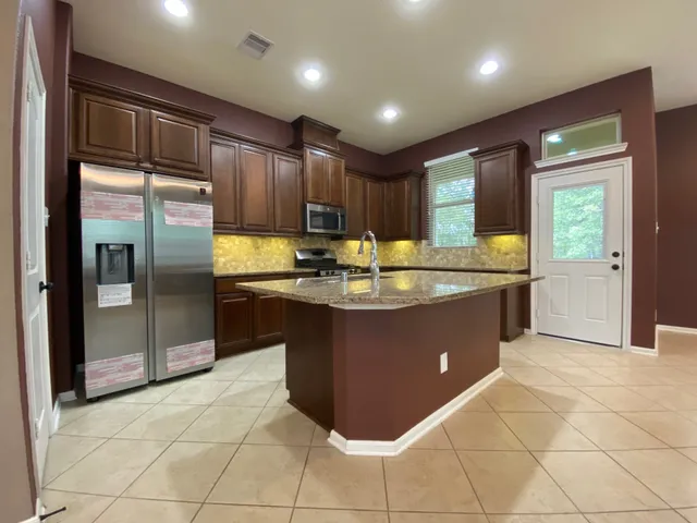 a kitchen with stainless steel appliances granite countertop a refrigerator and a sink