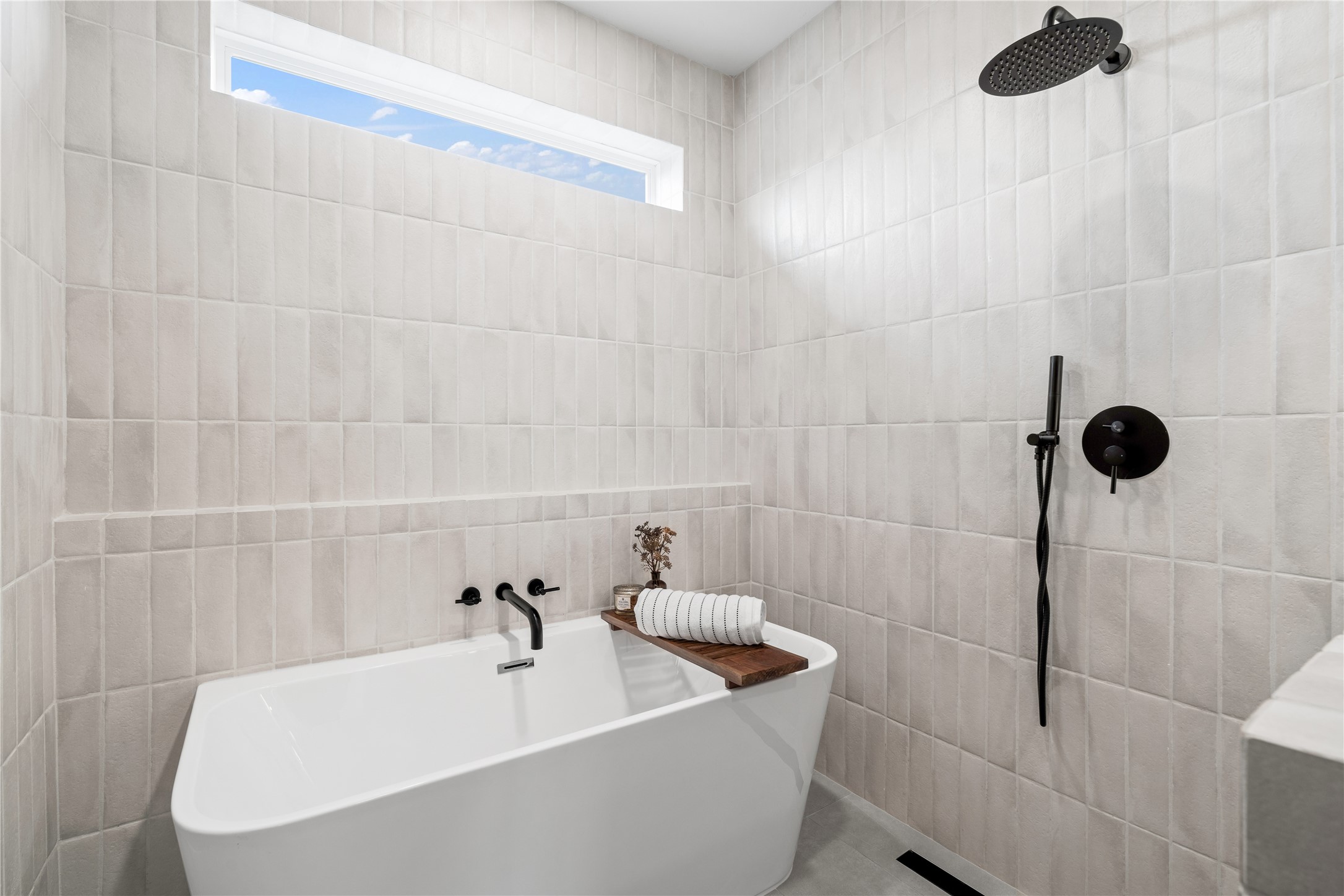 2950 Pitzlin Street Houston, TX 77023 - Photo 26 of 37 Tucked beneath a picture window and surrounded by floor-to-ceiling tile, this freestanding tub offers a luxurious escape within the walk-in wet room. Matte black fixtures and spa-style detailing create a serene, high-design space where you can unwind in total tranquility.