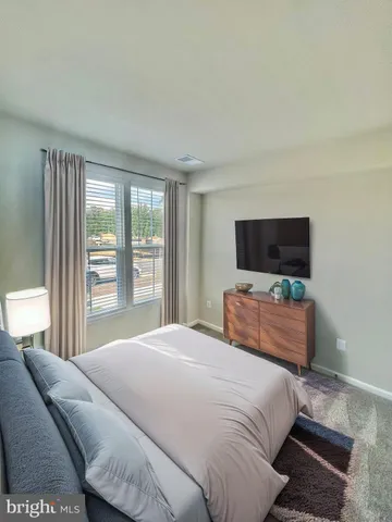 a bedroom with a bed television on desk and a window