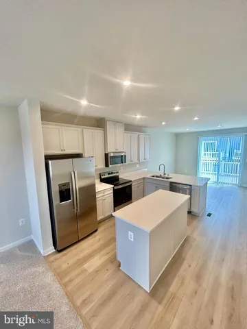 a large kitchen with a large counter top stainless steel appliances and wooden floor