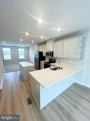 a large white kitchen with wooden floors and white stainless steel appliances