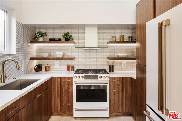 a kitchen with stainless steel appliances granite countertop a stove a refrigerator and a sink with wooden cabinets
