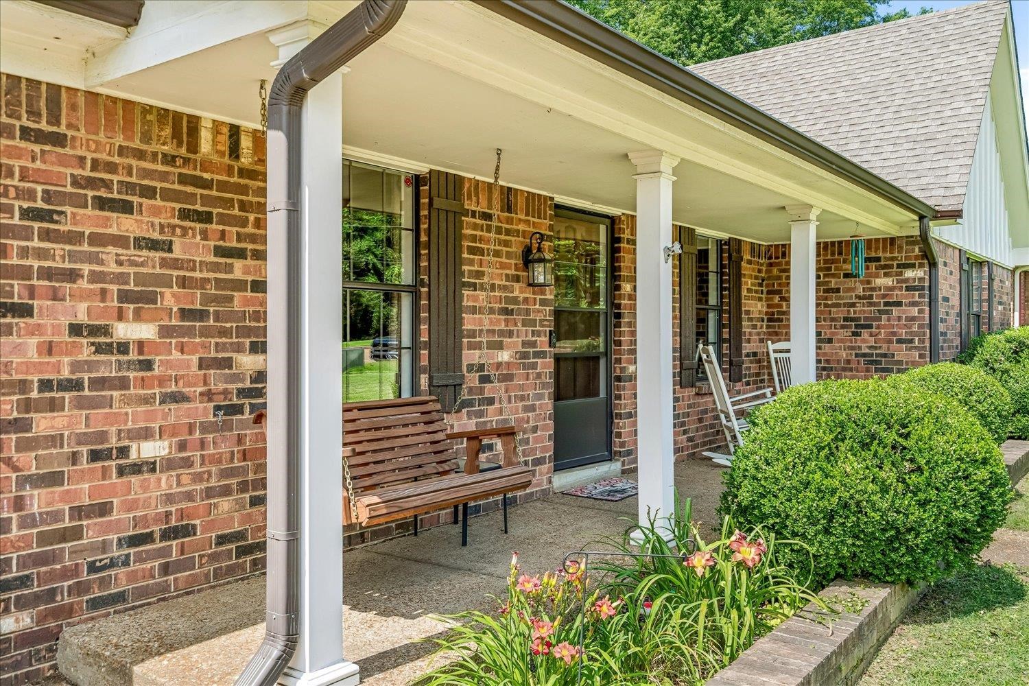 5711 Yale Road Bartlett, TN 38134 - Photo 22 of 29 Brick exterior with a covered front porch, featuring classic white columns and dark-framed windows with decorative shutters