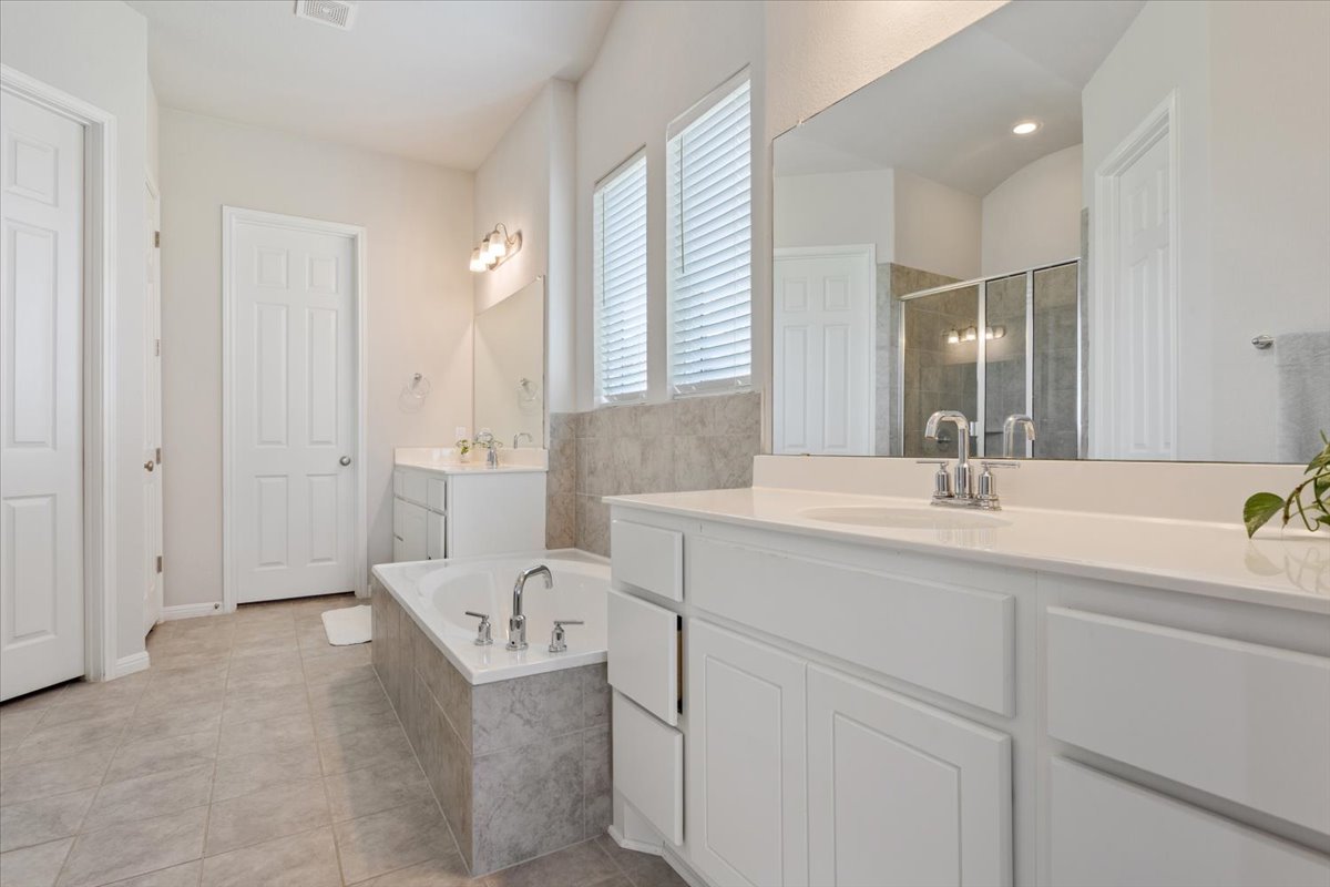 3625 Garrano Bend Leander, TX 78641 - Photo 16 of 38 Dual vanities and a deep soaking tub create a luxurious primary bathroom oasis.