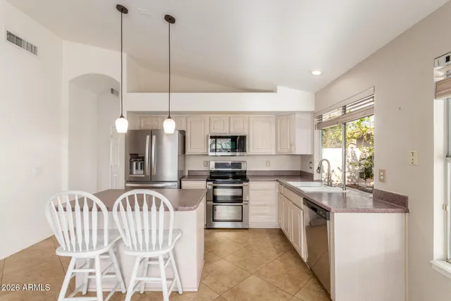 a kitchen with a sink a kitchen island a stove a dining table and chairs