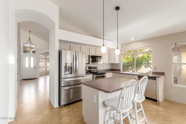 a kitchen with stainless steel appliances granite countertop a stove a refrigerator a sink a oven with a dining table and chairs