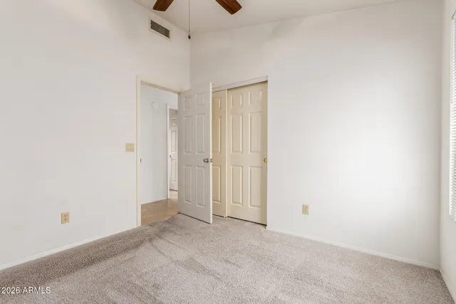 an empty room with ceiling fan and window