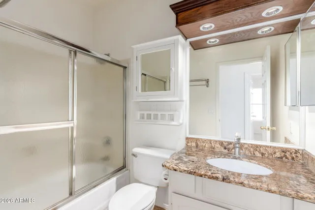a bathroom with a granite countertop sink toilet and shower