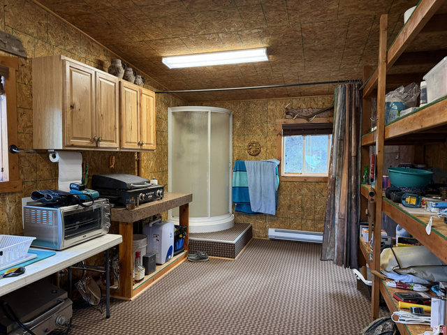 2006 Swenson Valley Road Bancroft, ID 83217 - Photo 43 of 51 Room featuring wood-finish paneling, a compact stand-up shower, built-in wooden shelving, and upper cabinetry