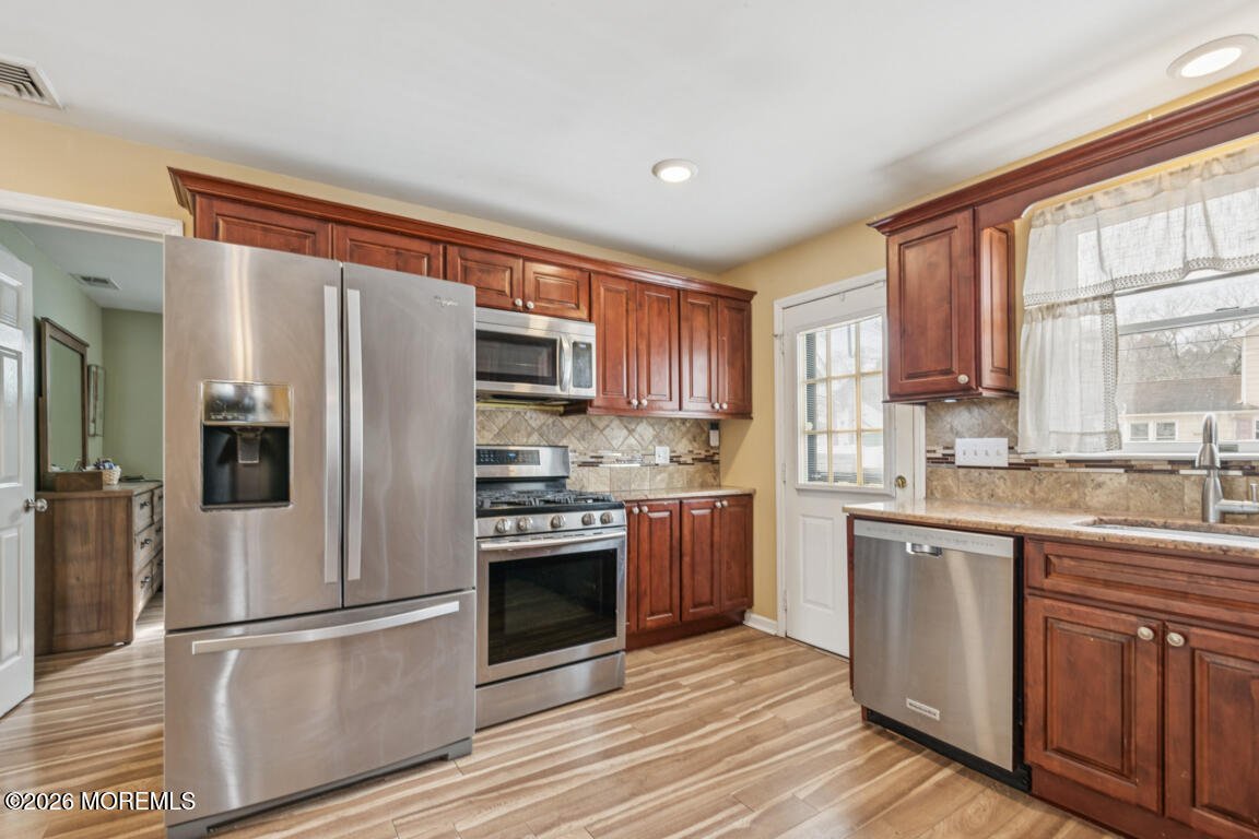 699 Mantoloking Road Brick, NJ 08723 - Photo 15 of 35 a kitchen with stainless steel appliances granite countertop a refrigerator a stove top oven a sink and dishwasher with wooden floor