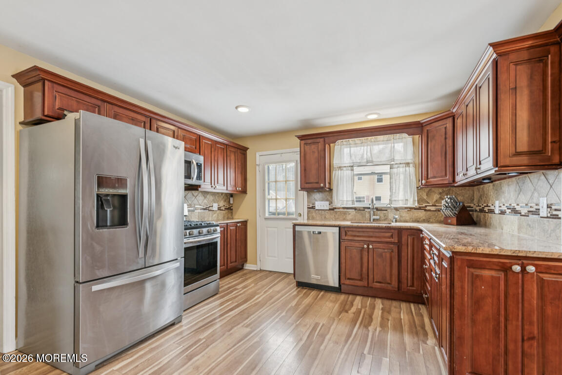 699 Mantoloking Road Brick, NJ 08723 - Photo 18 of 35 a kitchen with stainless steel appliances granite countertop a refrigerator a stove top oven a sink and dishwasher with wooden floor