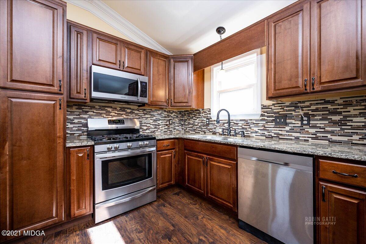 1939 Dames Ferry Road Forsyth, GA 31029 - Photo 3 of 29 a kitchen with stainless steel appliances granite countertop a stove a sink dishwasher and a microwave oven with wooden cabinets