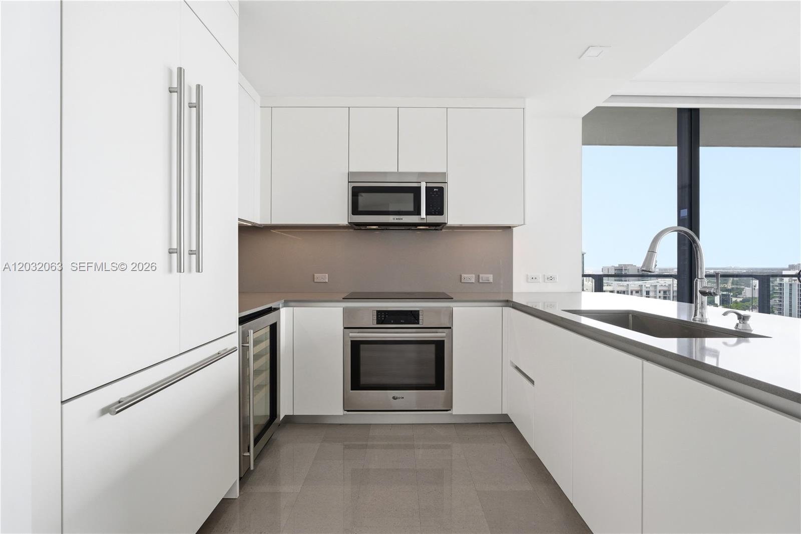 88 Southwest 7th Street, Unit 2302 Miami, FL 33130 - Photo 5 of 26 a kitchen with granite countertop white cabinets and stainless steel appliances