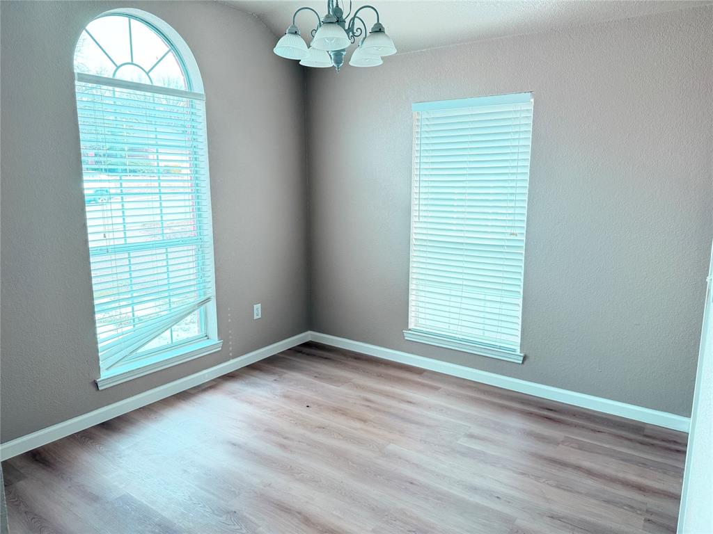 453 Strata Drive Denton, TX 76201 - Photo 11 of 15 an empty room with wooden floor chandelier and windows