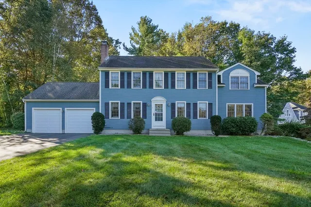 a brick house with a big yard and large trees