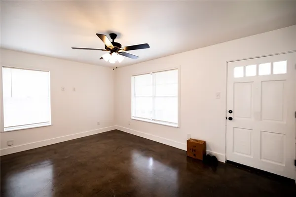 an empty room with wooden floor chandelier fan and windows